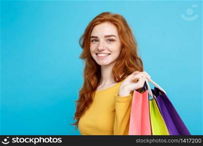 Shopping Concept - Close up Portrait young beautiful attractive redhair girl smiling looking at camera. Blue Pastel Background. Copy space.. Shopping Concept - Close up Portrait young beautiful attractive redhair girl smiling looking at camera with shopping bag. Blue Pastel Background. Copy space.