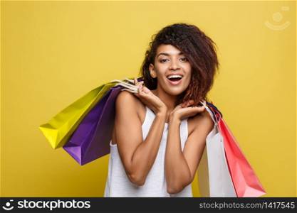 Shopping Concept - Headshot of Portrait young beautiful attractive African woman smiling and joyful with colorful shopping bag. Yellow Pastel wall Background. Copy Space. Shopping Concept - Headshot of Portrait young beautiful attractive African woman smiling and joyful with colorful shopping bag. Yellow Pastel wall Background. Copy Space.