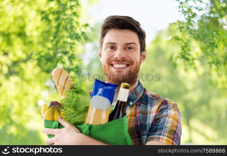 shopping, consumerism and people concept - smiling young man with food in bag over green natural background. smiling young man with food in bag