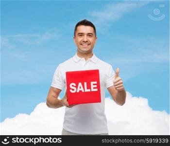 shopping, discount, consumerism, gesture and people concept - smiling man with red sale sigh showing thumbs up over blue sky and cloud background