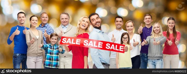 shopping, family, generation and people concept - group of happy men and women showing thumbs up and sale sign over holidays lights background