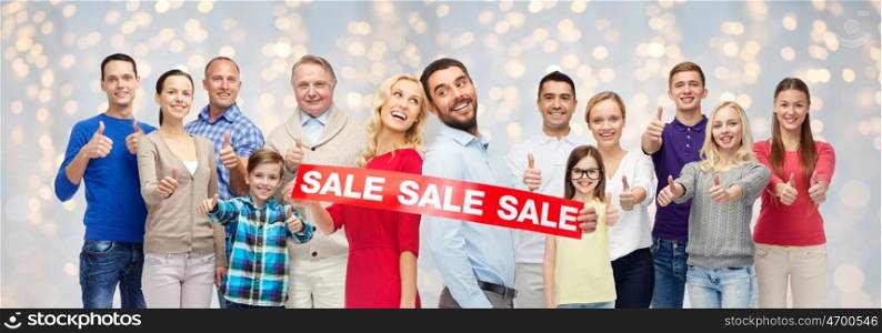 shopping, family, generation and people concept - group of happy men and women showing thumbs up and sale sign over holidays lights background