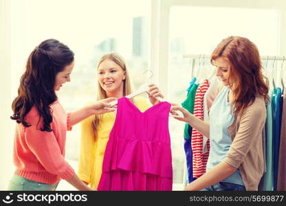 shopping, fashion and friendship concept - three smiling friends trying on some clothes at home or shopping mall