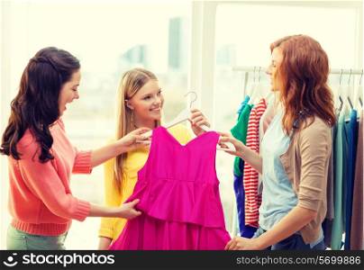 shopping, fashion and friendship concept - three smiling friends trying on some clothes at home or shopping mall