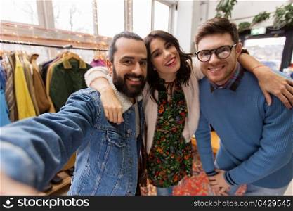 shopping, fashion and people concept - happy smiling friends taking selfie at vintage clothing store. friends taking selfie at vintage clothing store