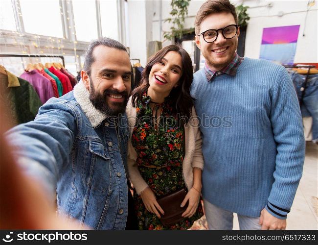 shopping, fashion and people concept - happy smiling friends taking selfie at vintage clothing store. friends taking selfie at vintage clothing store. friends taking selfie at vintage clothing store
