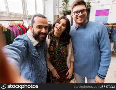 shopping, fashion and people concept - happy smiling friends taking selfie at vintage clothing store. friends taking selfie at vintage clothing store. friends taking selfie at vintage clothing store