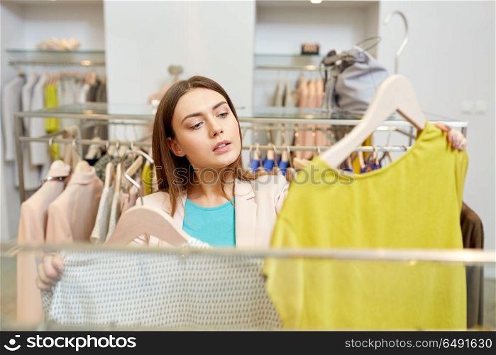 shopping, fashion, sale and people concept - young woman choosing clothes in mall or clothing store. woman choosing clothes at clothing store. woman choosing clothes at clothing store