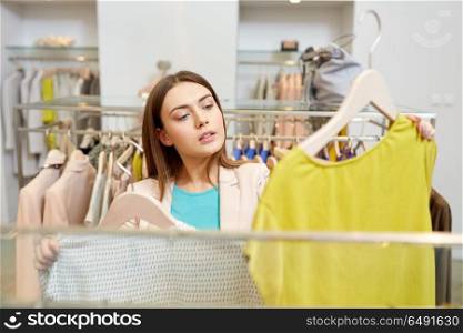 shopping, fashion, sale and people concept - young woman choosing clothes in mall or clothing store. woman choosing clothes at clothing store. woman choosing clothes at clothing store