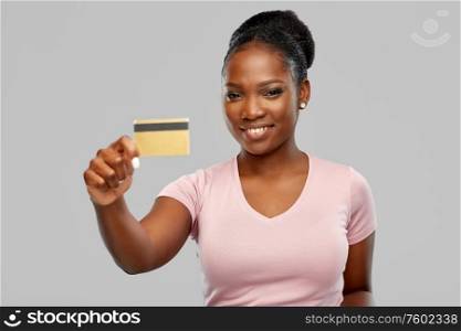 shopping, finance and people concept - happy smiling african american young woman with credit card over grey background. happy african american woman with credit card