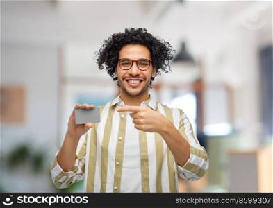 shopping, finance and people concept - happy smiling man with credit card over office background. happy smiling man with credit card at office