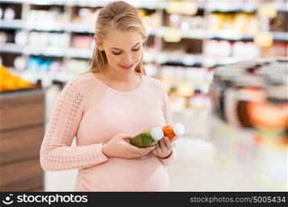 shopping, food, pregnancy, healthy eating and people concept - happy pregnant woman with juice bottles at grocery store or supermarket. happy pregnant woman with juice at grocery store