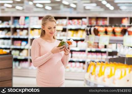 shopping, food, pregnancy, healthy eating and people concept - happy pregnant woman with juice bottles at grocery store or supermarket. happy pregnant woman with juice at grocery store