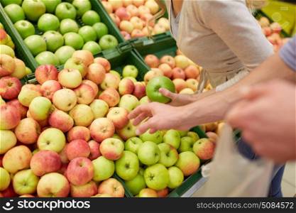 shopping, food, sale, consumerism and people concept - happy couple buying apples at grocery store or supermarket. happy couple buying apples at grocery store. happy couple buying apples at grocery store