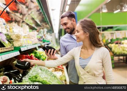 shopping, food, sale, consumerism and people concept - happy couple buying avocado at grocery store or supermarket