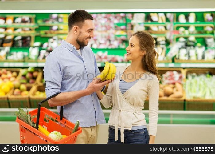 shopping, food, sale, consumerism and people concept - happy couple buying bananas at grocery store or supermarket