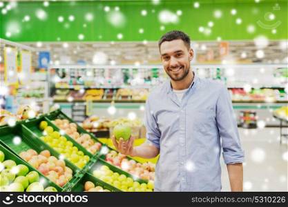 shopping, food sale, consumerism and people concept - happy man buying green apples at grocery store or supermarket over snow. happy man buying green apples at grocery store