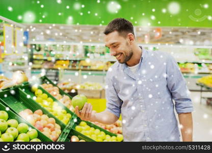 shopping, food sale, consumerism and people concept - happy man buying green apples at grocery store or supermarket over snow. happy man buying green apples at grocery store