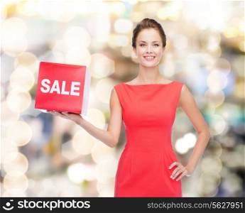 shopping, gifts, christmas and holiday concept - smiling young woman in dress with red sale sign