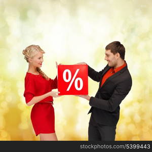 shopping, gifts, christmas, couple, x-mas concept - smiling woman and man with red percent sale sign