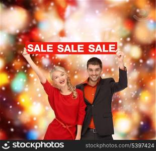 shopping, gifts, christmas, couple, x-mas concept - smiling woman and man with red sale sign