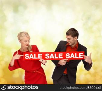 shopping, gifts, christmas, couple, x-mas concept - smiling woman and man with red sale sign