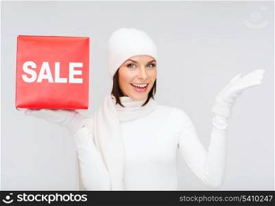 shopping, gifts, christmas, x-mas concept - smiling woman in winter clothes with red sale sign