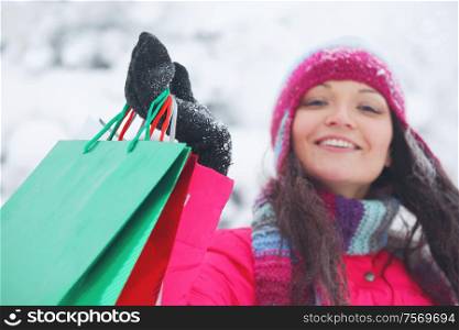 Shopping happy woman in snow covered park holding bags. Winter sales.. Shopping woman holding bags