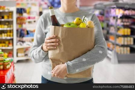 shopping, healthy eating and eco friendly concept - close up of woman with paper bag full of food over supermarket on background. close up of woman with paper bag full of food