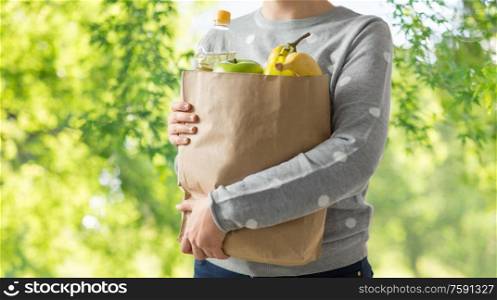shopping, healthy eating and eco friendly concept - close up of woman with paper bag full of food over green natural background. close up of woman with paper bag full of food