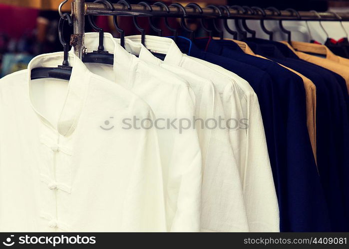 shopping, industry, sale and clothing concept - male oriental shirts on hanger at asian street market