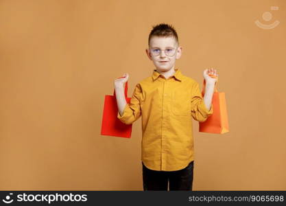 Shopping on black friday. Little boy holding shopping bags on yellow background. Shopper with many colored paper bags. Holidays sales and discounts. Cyber monday. High quality photo.. Shopping on black friday. Little boy holding shopping bags on yellow background. Shopper with many colored paper bags. Holidays sales and discounts. Cyber monday. High quality photo