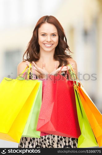shopping, presents and gifts - attractive woman holding color shopping bags in mall