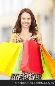 shopping, presents and gifts - attractive woman holding color shopping bags in mall