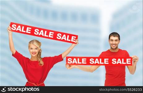 shopping, sale and christmas concept - woman and man with red sale signs outdoors