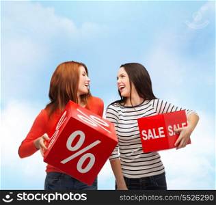shopping, sale and gift sconcept - two smiling teenage girls with percent and sale sign on red box
