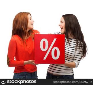 shopping, sale, and gift sconcept - two smiling teenage girls with percent sign on red box