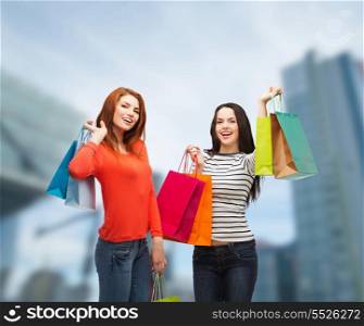 shopping, sale and gifts concept - two smiling teenage girls with shopping bags