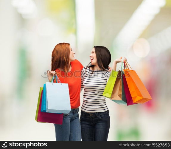 shopping, sale and gifts concept - two smiling teenage girls with shopping bags