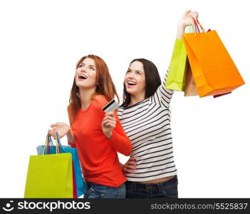 shopping, sale and gifts concept - two smiling teenage girls with shopping bags and credit card