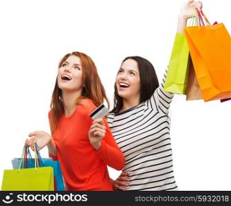shopping, sale and gifts concept - two smiling teenage girls with shopping bags and credit card