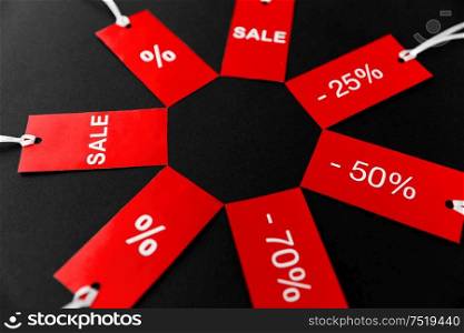shopping, sale and outlet concept - red tags with discount signs on black background. red tags with discount signs on black background