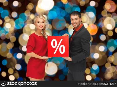 shopping, sale and people concept - happy couple with discount sign over christmas lights background. couple with discount sign over christmas lights