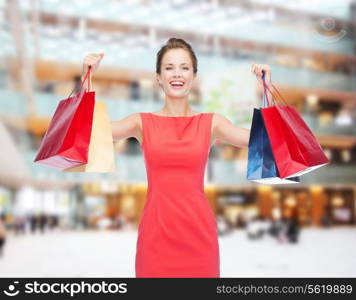 shopping, sale, christmas and holiday concept - laughing elegant woman in red dress with shopping bags