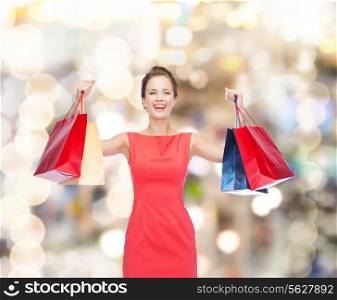 shopping, sale, christmas and holiday concept - laughing elegant woman in red dress with shopping bags