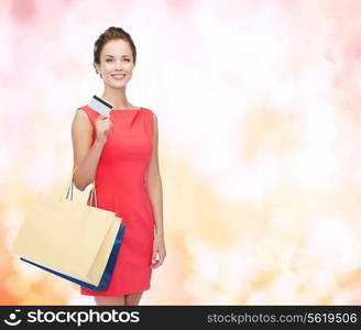 shopping, sale, christmas and holiday concept - smiling elegant woman in red dress with shopping bags and plastic card