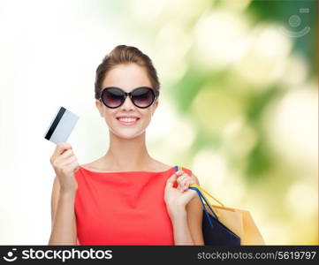 shopping, sale, christmas and holiday concept - smiling elegant woman in red dress with shopping bags and plastic card