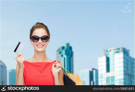 shopping, sale, christmas and holiday concept - smiling elegant woman in red dress with shopping bags and plastic card