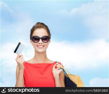 shopping, sale, christmas and holiday concept - smiling elegant woman in red dress with shopping bags and plastic card