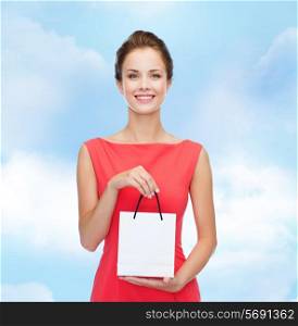 shopping, sale, christmas and holiday concept - smiling elegant woman in red dress with small shopping bag